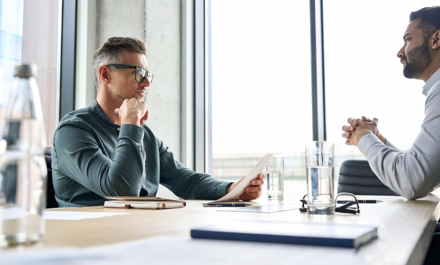 Two executives reviewing due diligence documents across a boardroom table in Dubai